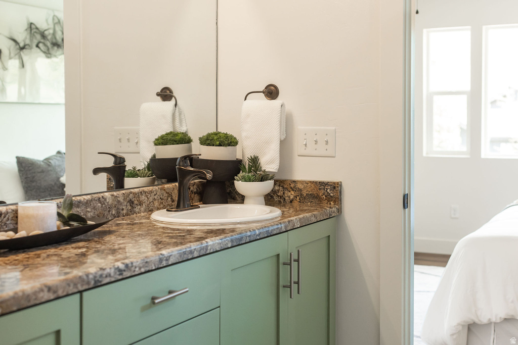 Bathroom vanity featuring a drop-in sink, dark bronze faucet, and a stone-look countertop