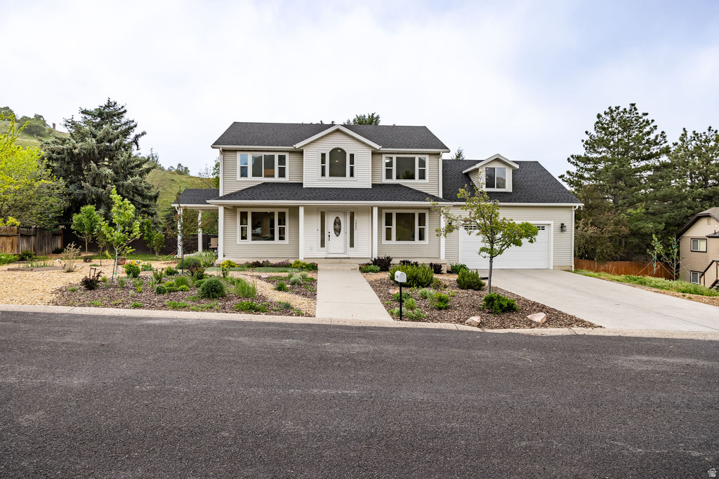 Two-story residence featuring a light-toned exterior and dark shingle roofing