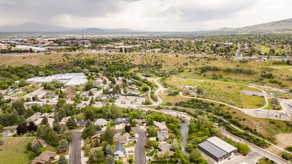 Expansive aerial perspective showcasing a residential neighborhood with mature trees, winding roads, and a visible waterway