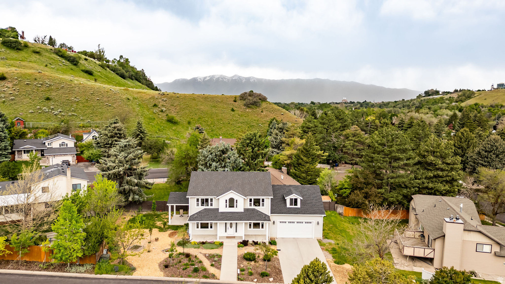 Contemporary two-story residence featuring a light-toned exterior, dark shingle roof, and an attached two-car garage