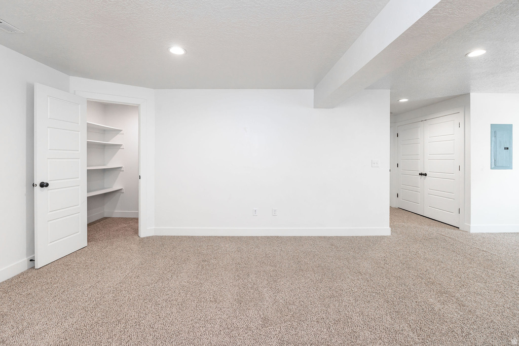 Open space with light neutral carpeting, recessed lighting, white walls, and a convenient storage closet with built-in shelving