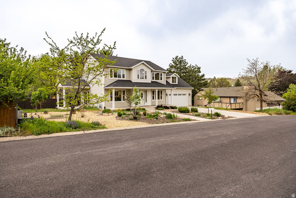 Two-story residence featuring light-toned siding, a dark shingle roof, and a prominent front porch