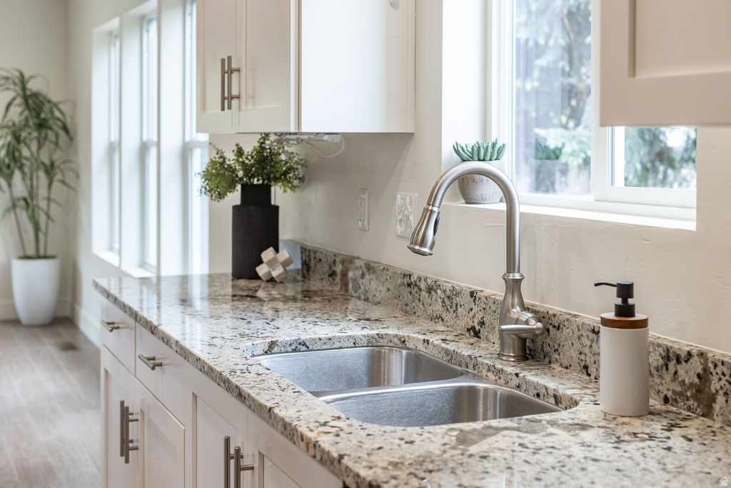 Kitchen featuring granite countertops, a double basin stainless steel sink, a brushed nickel pull-down faucet, white shaker cabinetry with brushed nickel hardware, and wood-finish flooring