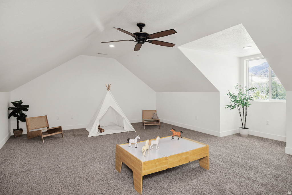 Spacious attic room featuring sloped ceilings, recessed lighting, a ceiling fan, and gray carpet flooring