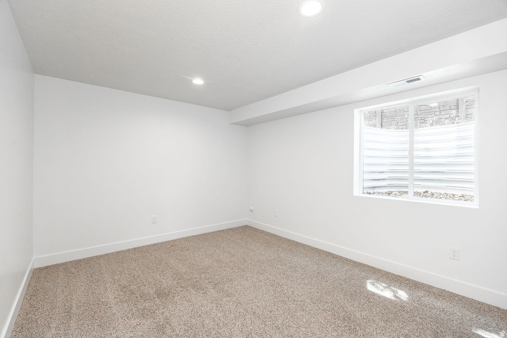 Carpeted room featuring recessed lighting, a window with white blinds, and white baseboards