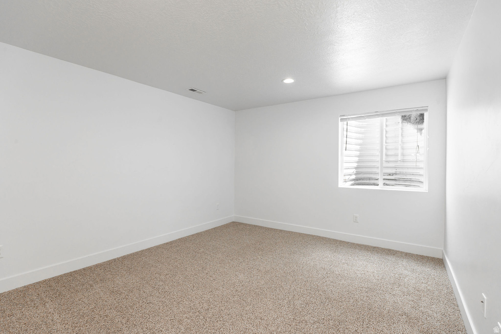 Carpeted room with white walls, recessed lighting, and a single window featuring horizontal blinds