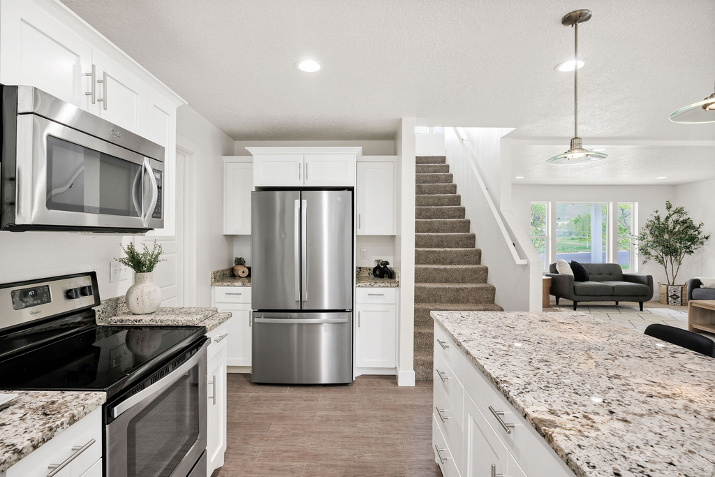 Kitchen featuring white cabinetry, stainless steel appliances, and wood-finish flooring