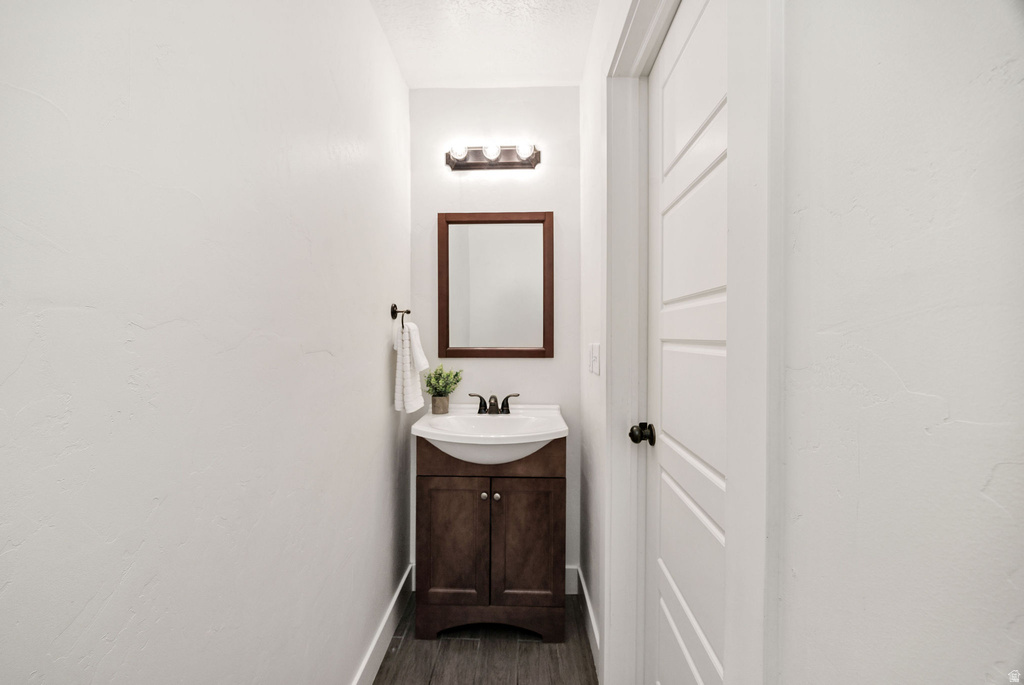Powder room featuring a dark wood-finish vanity with a white ceramic basin sink, a wood-framed mirror, and a three-light vanity fixture