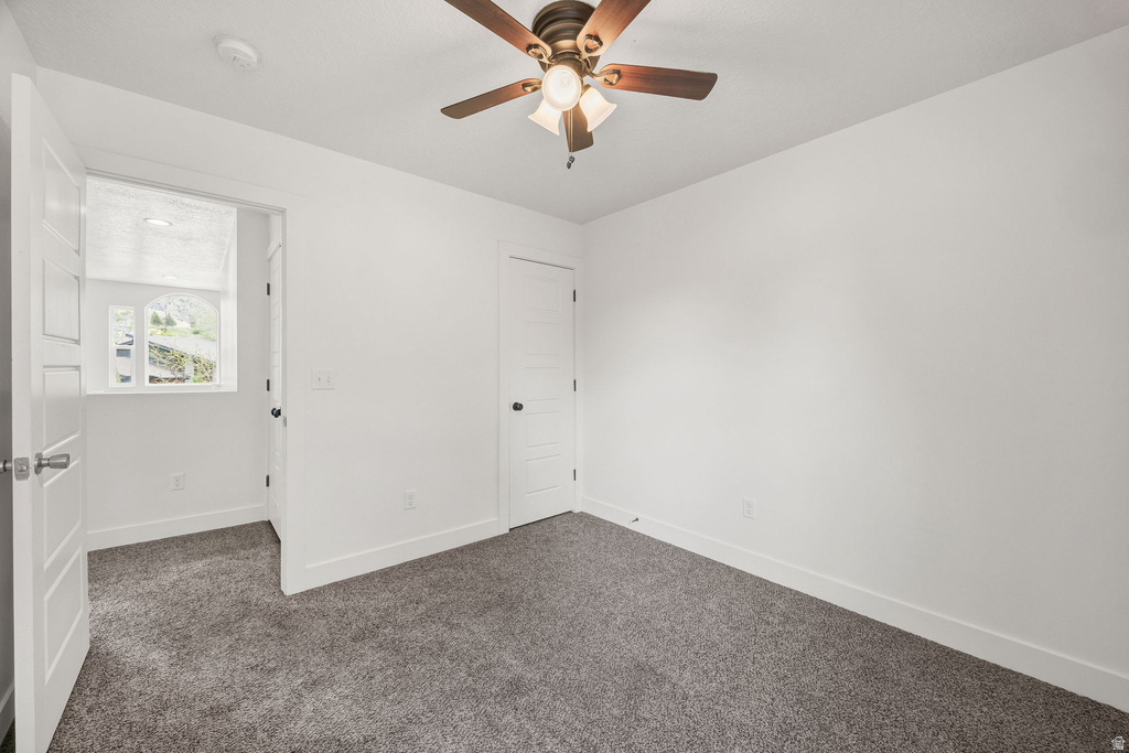 Room featuring grey carpet, white walls, and a ceiling fan with integrated lighting