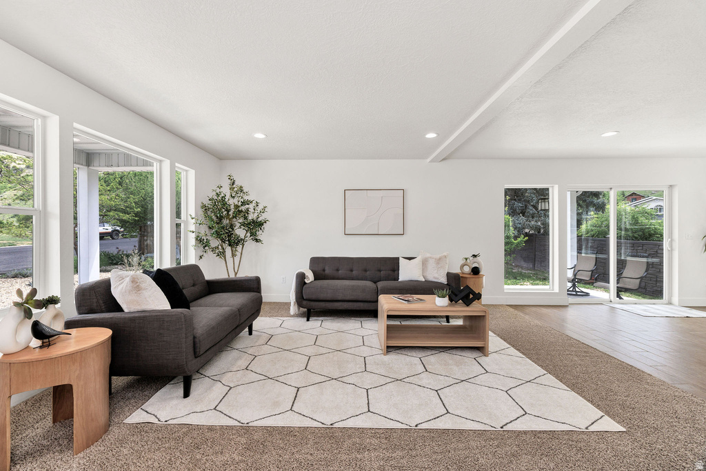 Spacious living area featuring large windows, sliding glass door access to the exterior, recessed lighting, and a combination of carpet and wood-finish flooring