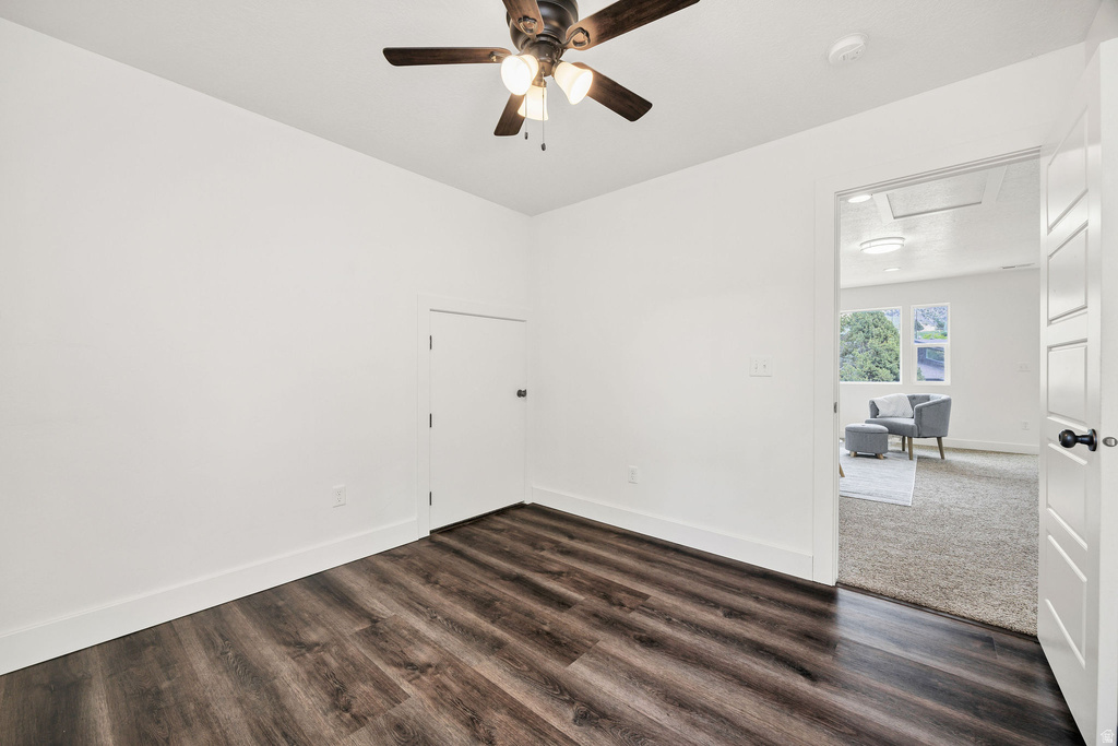 Room featuring wood-finish flooring, white baseboards, a ceiling fan with integrated lighting, and a white door with black hardware