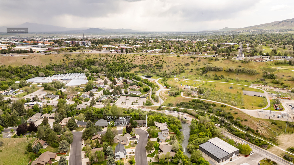 Aerial perspective showcasing a residential neighborhood with surrounding green spaces and distant mountains