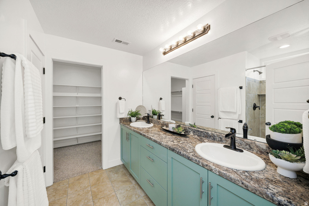 Bathroom vanity featuring dual sinks with matte black fixtures, extensive countertop space, and light teal cabinetry
