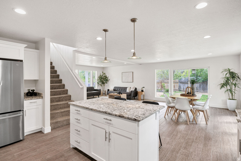 Kitchen island with a light-toned countertop, white cabinetry, and pendant lighting