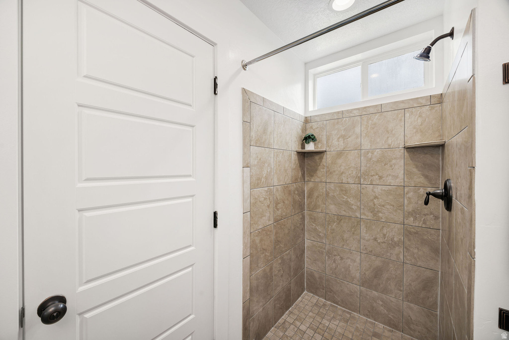 Shower stall with tiled walls and floor, featuring two built-in niches, a bronze-finish shower head, and a transom window