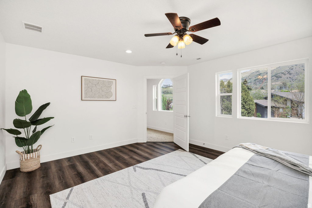 Spacious room featuring dark wood-finish flooring, a ceiling fan with integrated lighting, recessed lighting, and white trim