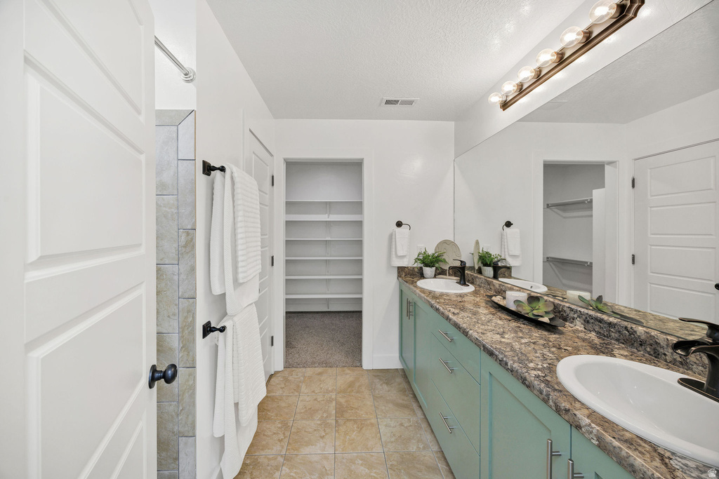 Bathroom featuring a dual-sink vanity with a textured countertop and light blue cabinetry