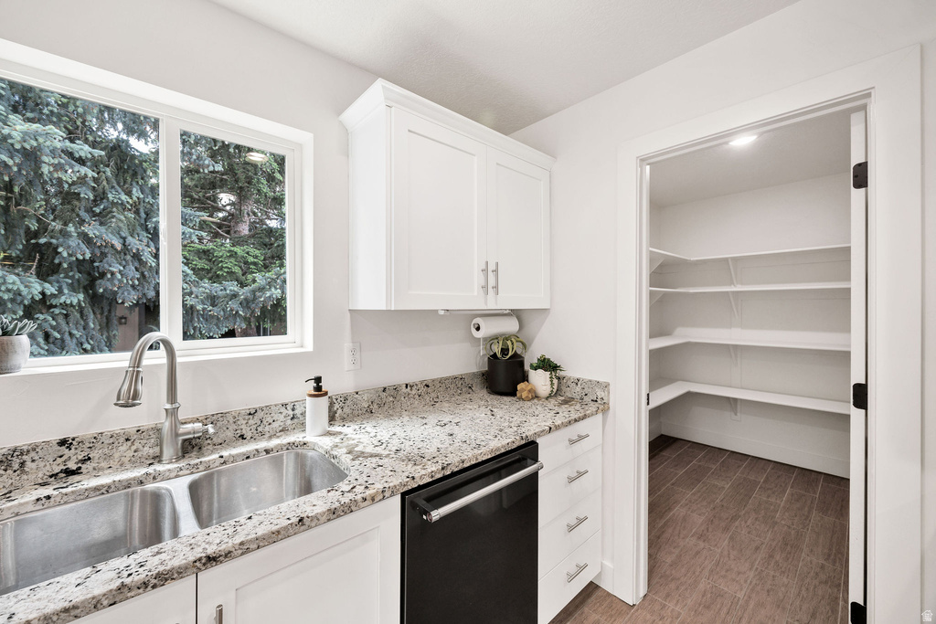Kitchen featuring white cabinetry, speckled countertops, a double basin stainless steel sink with gooseneck faucet, and a built-in dishwasher