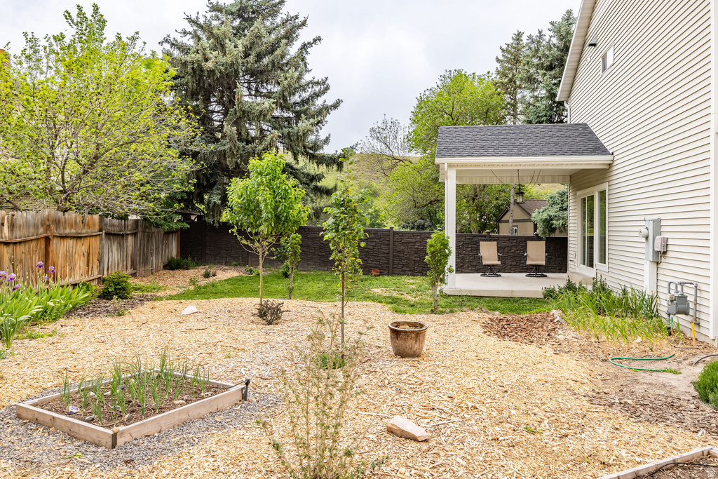 Rear exterior featuring a covered patio with a concrete slab, white columns, and dark shingle roofing