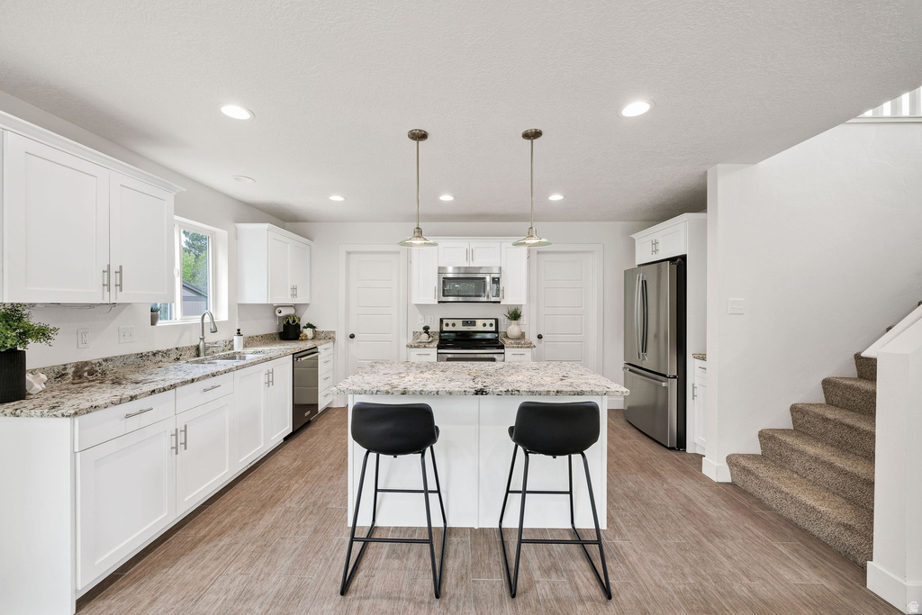 Kitchen featuring white shaker-style cabinetry, stainless steel appliances, granite countertops, and wood-finish flooring