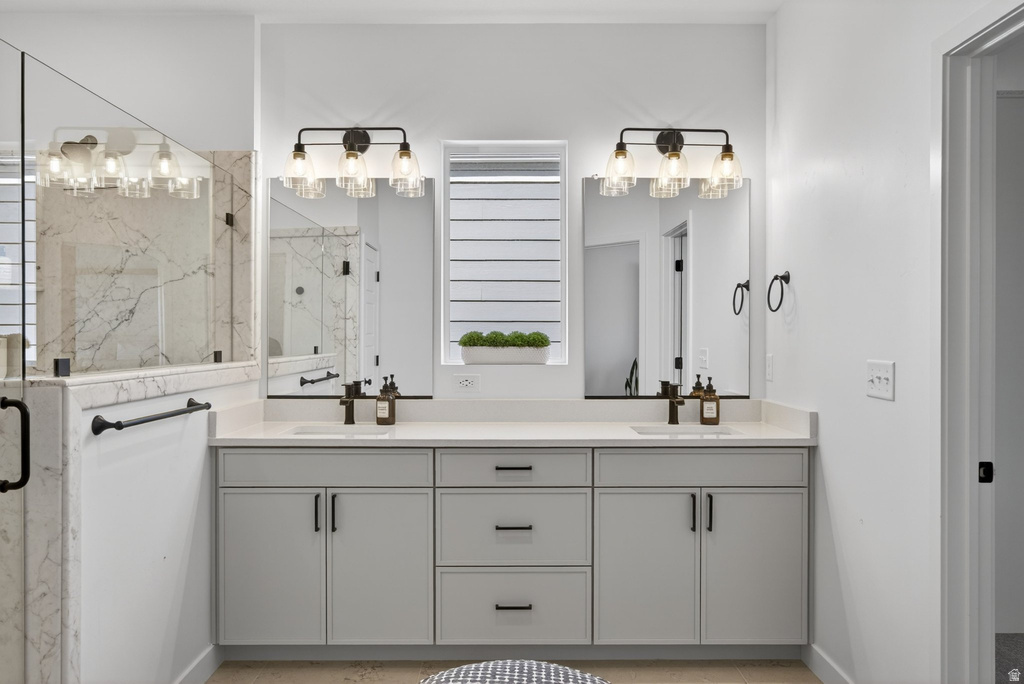 Double vanity featuring light gray cabinetry, integrated sinks with matte black faucets, and light-toned countertops