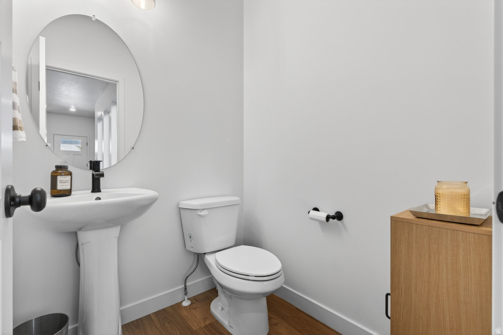 Pedestal sink with a matte black faucet, complemented by a circular wall-mounted mirror
