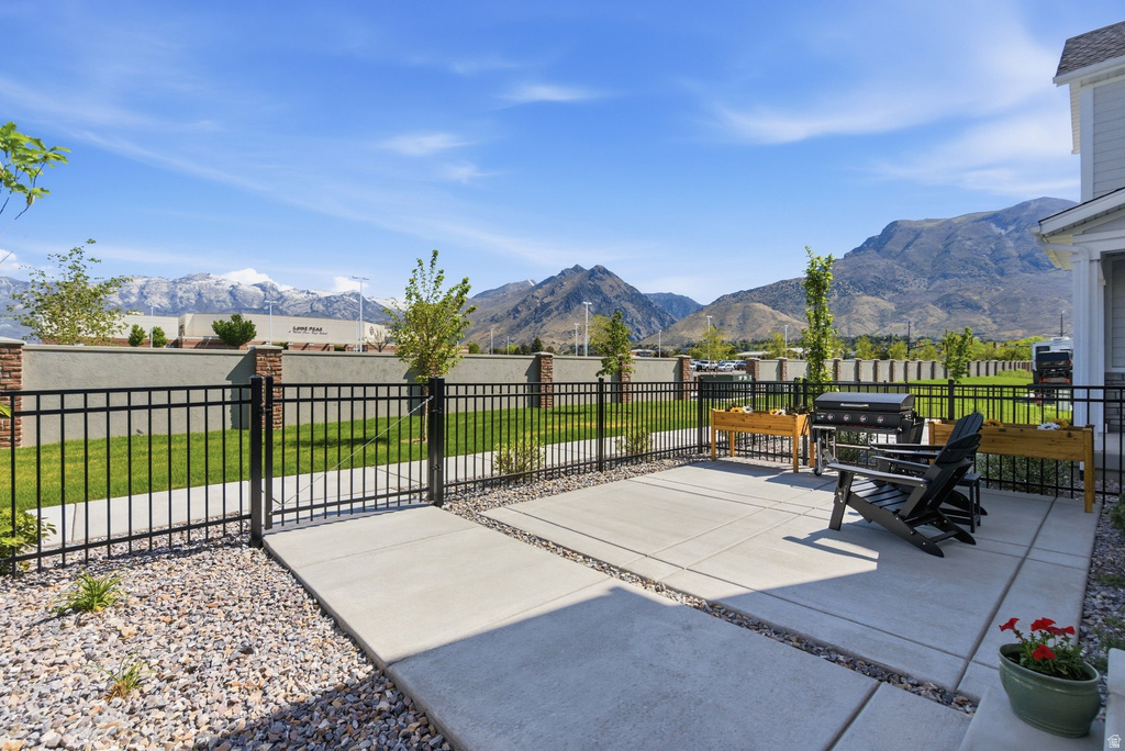 Expansive concrete patio bordered by decorative gravel, featuring a black metal fence and a manicured lawn