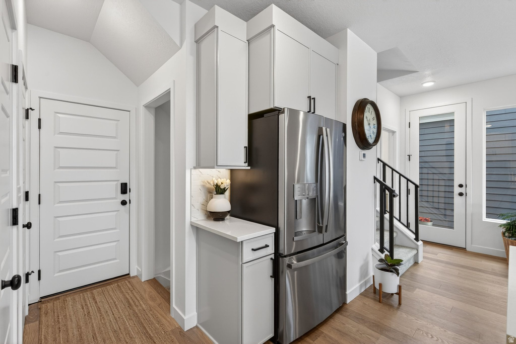 Contemporary kitchen cabinetry with integrated stainless steel refrigerator, white quartz-finish countertop, and under-cabinet lighting