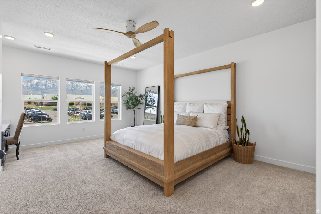 Spacious room featuring three large windows showcasing mountain scenery, light neutral carpet, recessed lighting, and a ceiling fan