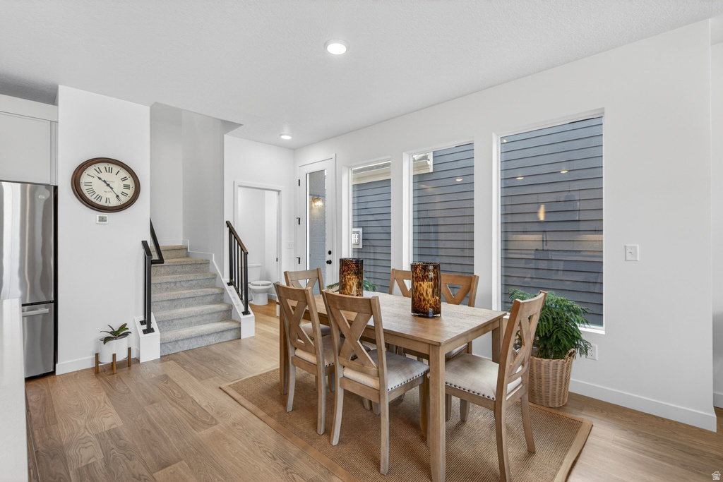 Open-concept dining area featuring wood-finish flooring, recessed lighting, and multiple windows