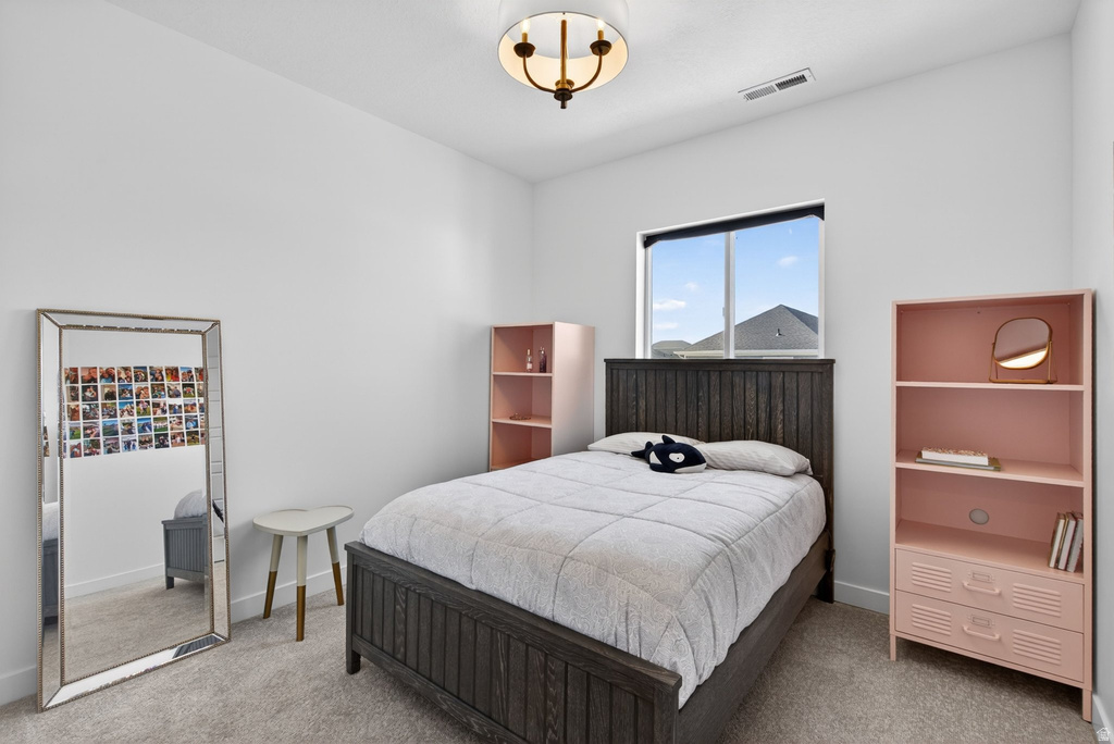 Bedroom featuring a centered window, light-colored carpeting, white walls, a built-in overhead light fixture, and a dark wood-finish headboard