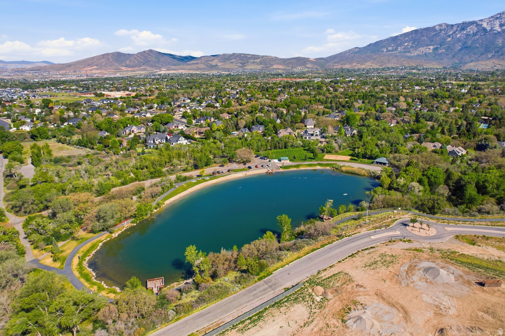 Expansive water feature with surrounding green spaces, paved pathways, and a sandy shoreline