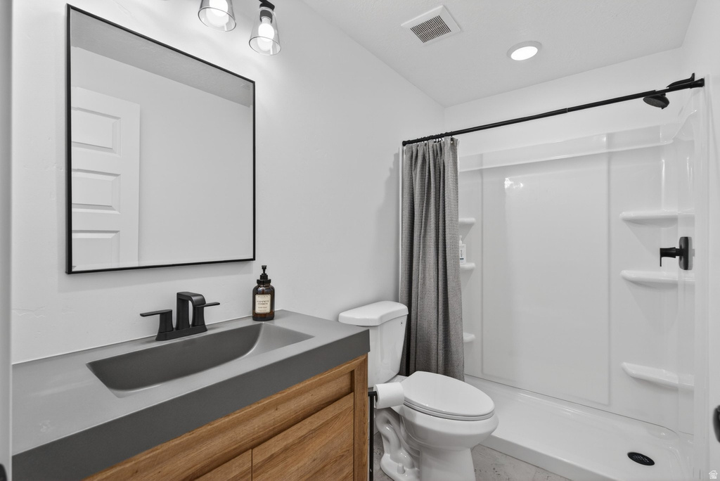 Bathroom featuring a wood-finish vanity with integrated sink, black fixtures, and a framed mirror