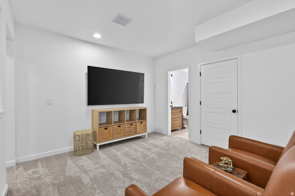 Spacious carpeted room featuring a wall-mounted display, recessed lighting, and a white five-panel interior door