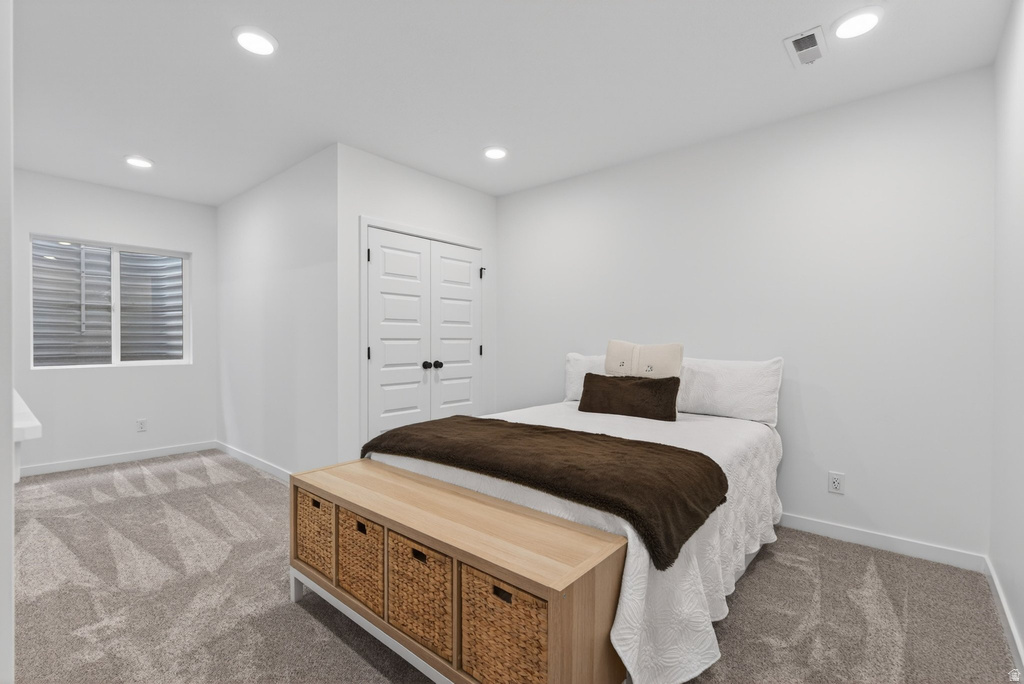 Spacious room featuring neutral carpeting, a double-door closet with black hardware, a window with horizontal blinds, and recessed lighting