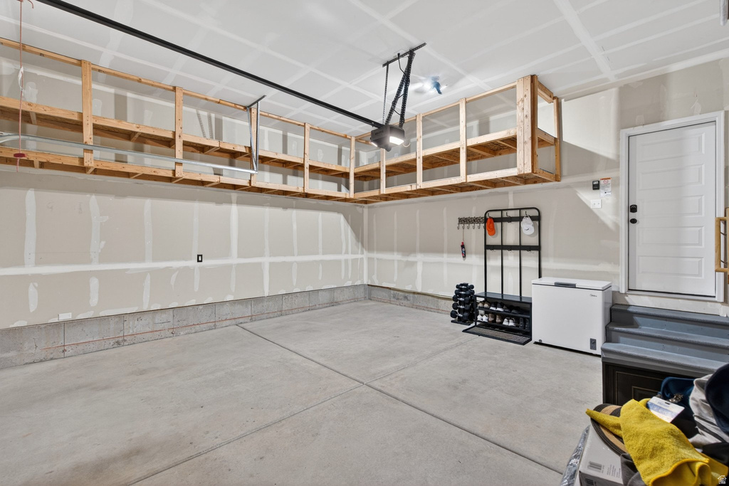 Spacious garage featuring a concrete floor, built-in overhead storage shelving, and an automatic garage door opener