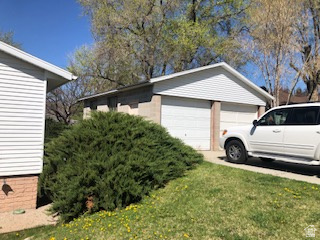 Detached two-car garage with white paneled garage doors, white siding, and a concrete driveway