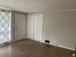 Entry area featuring wood-finish flooring, a paneled door with brass hardware, and bi-fold closet doors