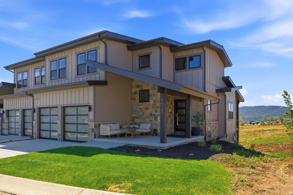 Contemporary multi-level exterior featuring tan siding, stone accents, and dark trim