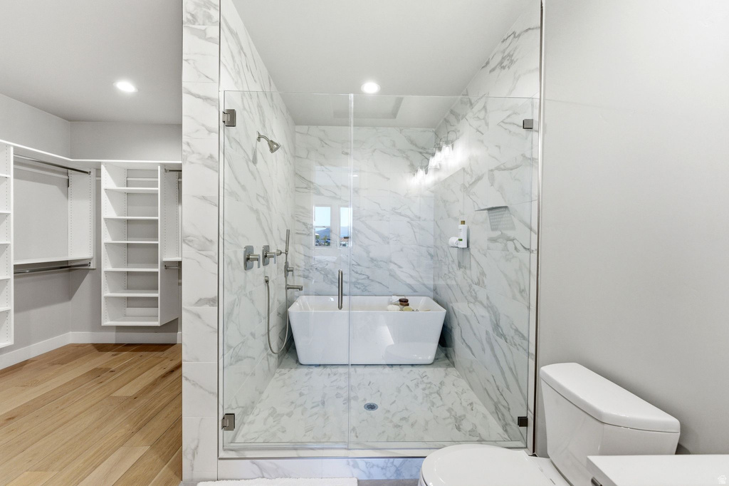 Glass-enclosed wet room featuring a freestanding soaking tub and full-height marble-style tile