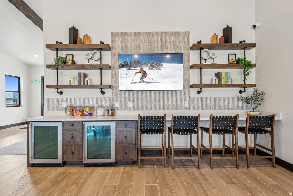 Entertainment bar featuring a television, two beverage refrigerators, and wood-finish flooring