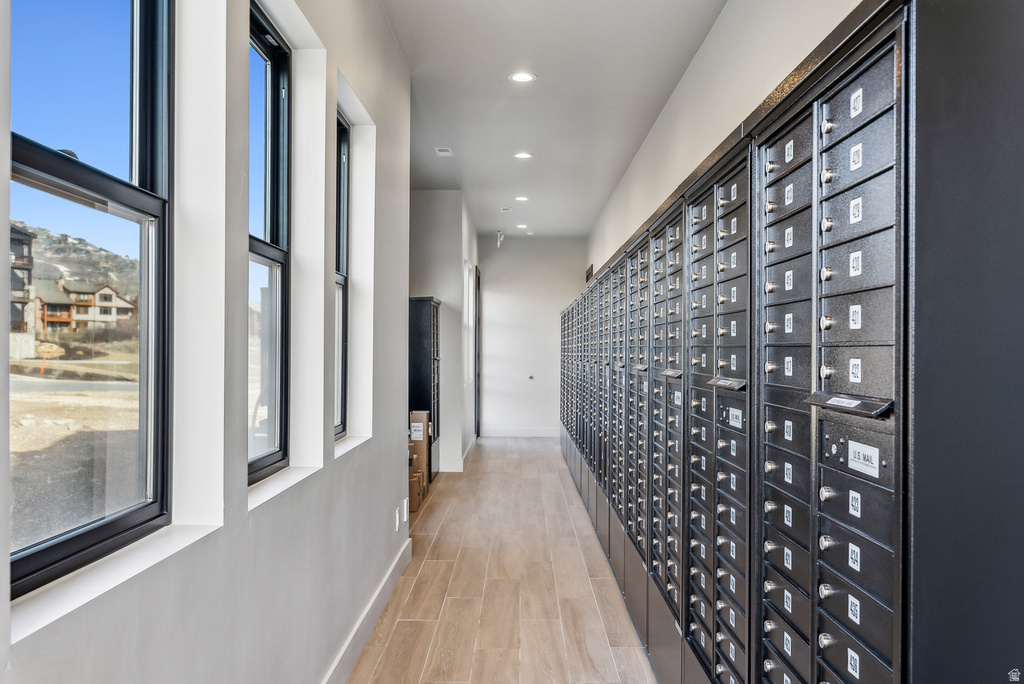 Hallway featuring a wall of dark individual mailboxes, recessed ceiling lighting, and light wood-finish flooring