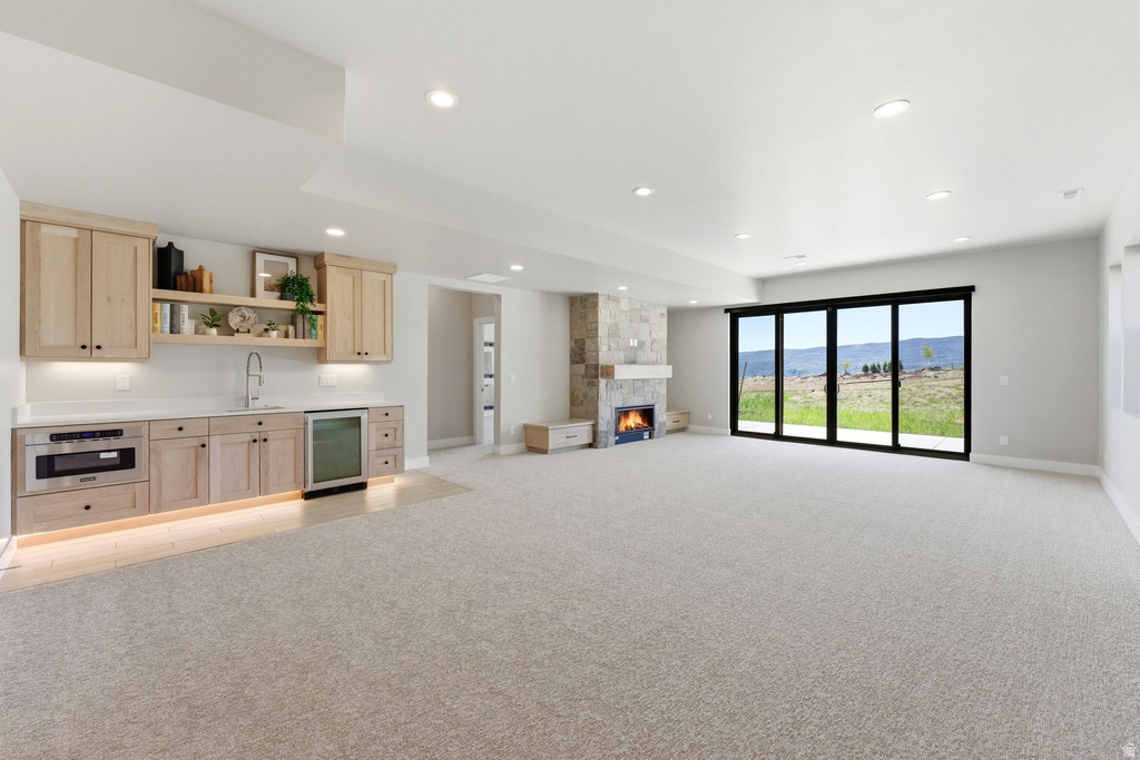 Spacious room featuring a built-in wet bar with wood cabinetry, integrated microwave, beverage cooler, and open shelving