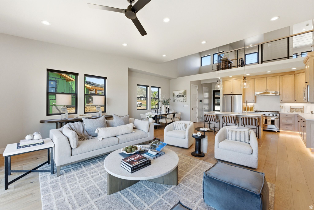 Open-concept living area with high ceilings, recessed lighting, and light wood-finish flooring