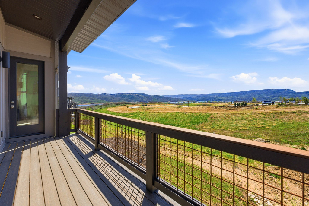 Expansive outdoor deck featuring wood-finish flooring, dark-framed mesh railing, and a full-light entry door