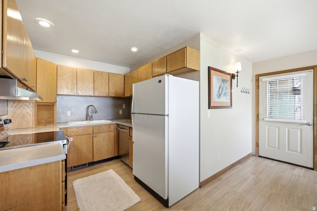 Functional kitchen featuring wood cabinetry, white appliances, recessed lighting, and wood-finish flooring