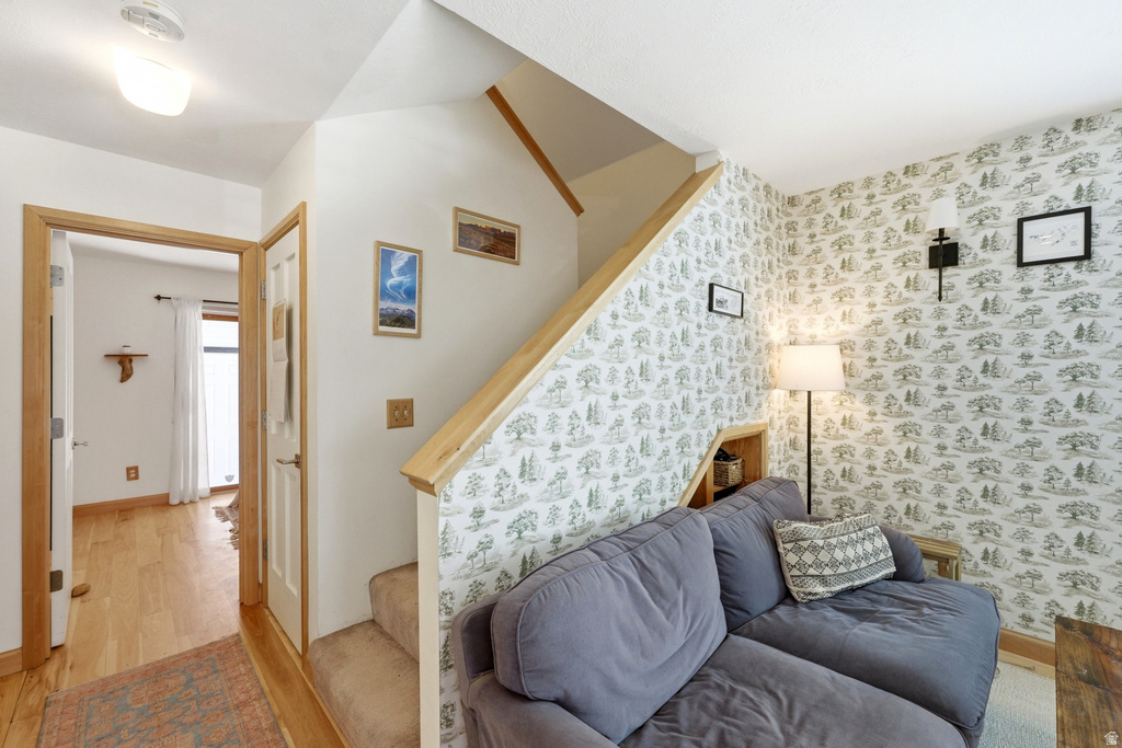 Carpeted staircase with light wood handrail, built-in shelving, and patterned wallpaper