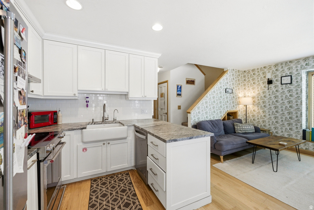 Kitchen featuring white shaker cabinetry, white subway tile backsplash, farmhouse sink, stainless steel dishwasher, and stone countertops