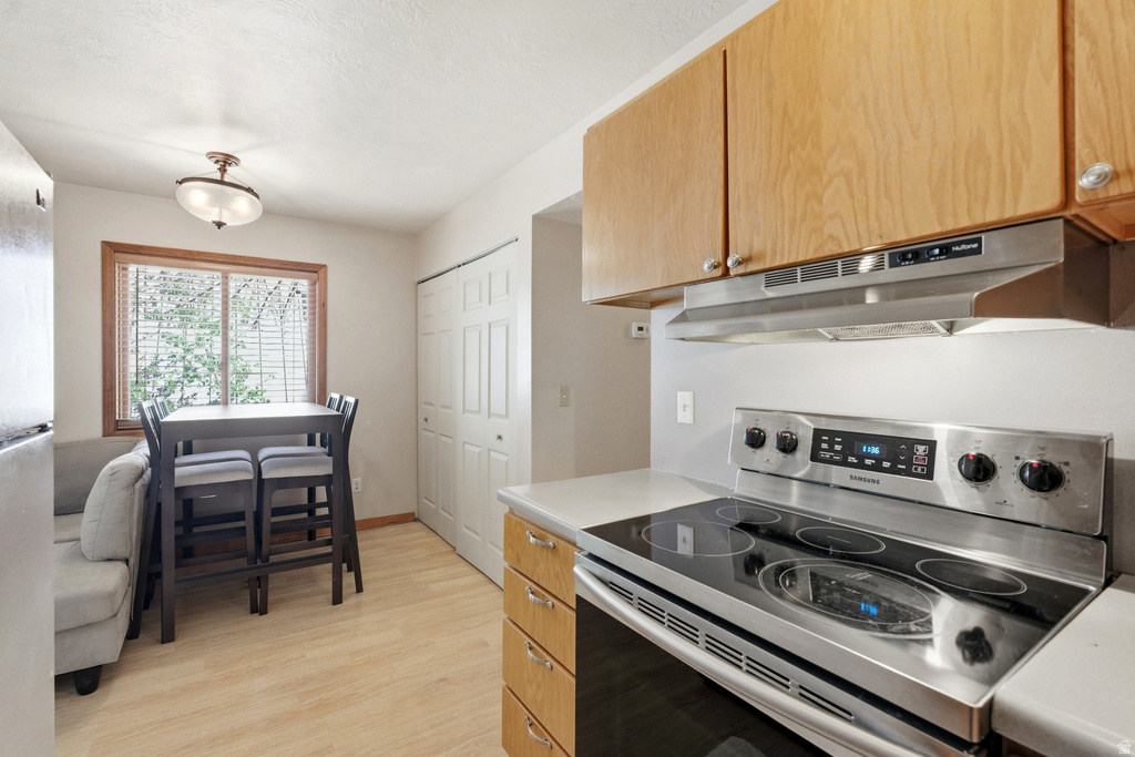 Kitchen area featuring light wood-finish flooring and a window with wood trim