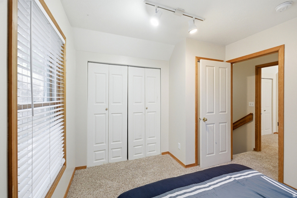 Carpeted room featuring a window with wood trim, white blinds, and white bi-fold closet doors